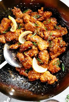 a pan filled with chicken and lemons on top of a table next to spices