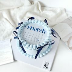 a blue and white cake sitting on top of a table next to an envelope with the word march written on it