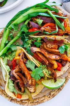 several tacos with meat, vegetables and sauces on a wicker platter