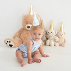 a baby wearing a party hat sitting in front of stuffed animals