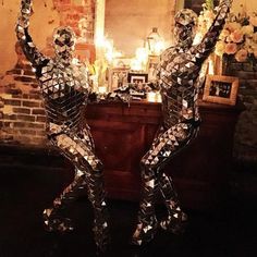 two shiny metal figures in front of a fireplace