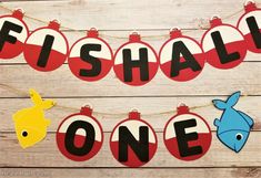 fishall one banner hanging on a string with paper cutouts in the shape of christmas balls