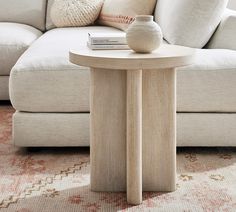 a white couch sitting next to a table on top of a rug