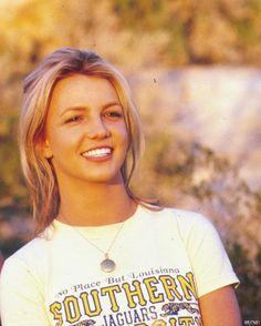 a woman in a white shirt is holding a frisbee and smiling at the camera