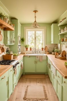 a kitchen filled with lots of green cabinets and wooden counter tops next to a window