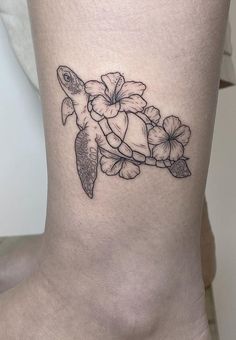 a small turtle and flowers tattoo on the side of a woman's lower leg