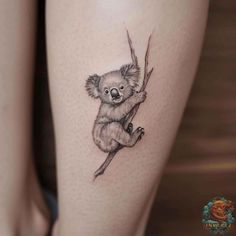 a small koala bear tattoo on the thigh, it looks like he is hanging from a tree branch