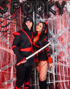 a man and woman dressed in costumes posing for a photo with the backdrop behind them