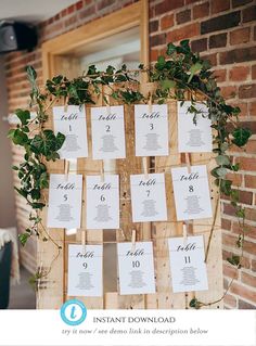 a wooden table with seating cards and greenery on it