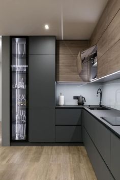 a modern kitchen with wooden floors and gray cabinetry on the wall, along with stainless steel appliances