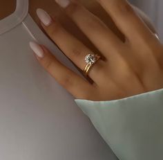 a woman's hand wearing a gold ring with a single diamond on the middle