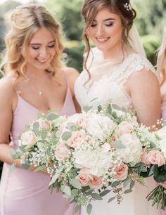 two bridesmaids holding bouquets of flowers and greenery