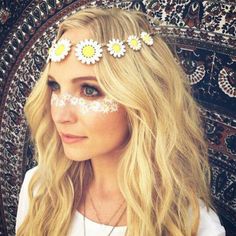 a woman with flowers in her hair and white face paint is posing for the camera