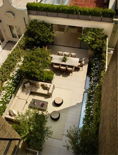 an aerial view of a courtyard with tables and chairs in the center, surrounded by greenery