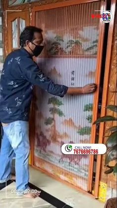 a man wearing a face mask standing in front of a bamboo screen with chinese writing on it