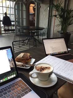 two laptops are sitting on a table with coffee and pastries in front of them