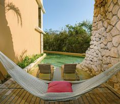 a hammock sitting on top of a wooden floor next to a swimming pool