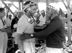 black and white photograph of two men shaking hands in front of other men wearing hats