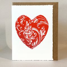 a red heart shaped card on a white background with a brown border around the edges