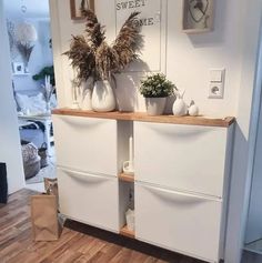 two white vases sitting on top of a wooden shelf in front of a door