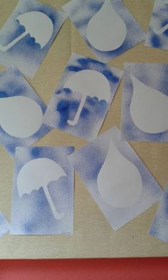 several pieces of paper cut out to look like watercolor umbrellas and raindrops