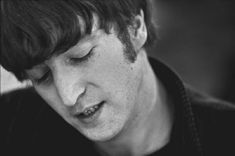 black and white photograph of a young man with his eyes closed looking down at his cell phone