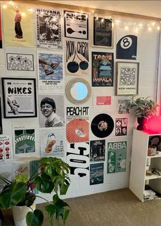 a room filled with lots of posters on the wall next to a potted plant