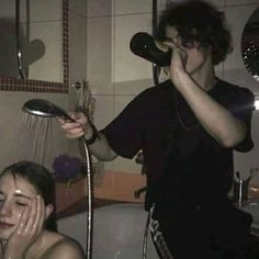 a woman is drying her hair in the shower while a man holds his hand up to his face