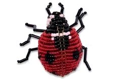 a red and black beaded ladybug sitting on top of a white surface