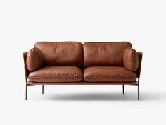 a brown leather couch sitting on top of a white floor next to a wooden frame