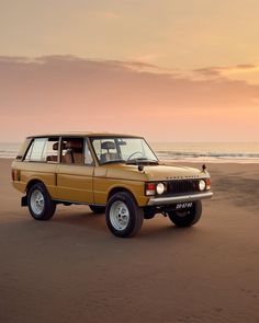 an suv parked on the beach at sunset