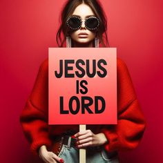 a woman wearing sunglasses holding a sign that says jesus is lord in front of her face