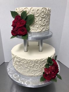 two tiered wedding cake with red roses on each layer and silver plated serving platter