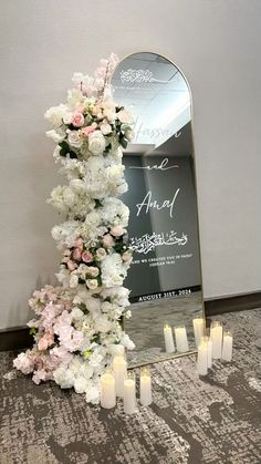 a tall mirror sitting on top of a carpeted floor next to flowers and candles