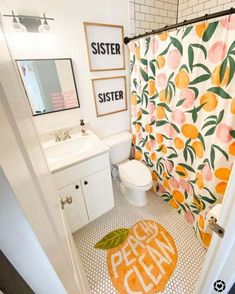 a bathroom with orange and white decor on the shower curtain, toilet seat cover and rug