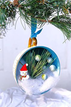 a christmas ornament hanging from a pine tree with snow and ornaments in it