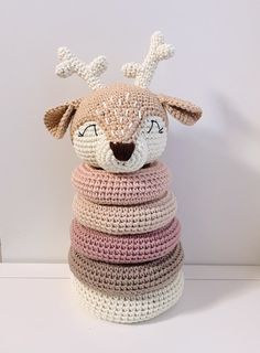 a crocheted stuffed animal sitting on top of a stack of knitted blankets