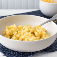 two bowls filled with macaroni and cheese on top of a blue place mat