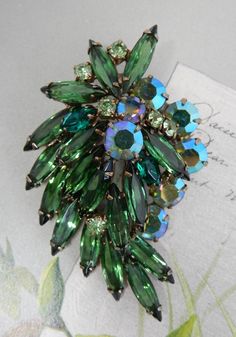 "Here's a pretty green brooch, shaped like a leaf, in green navette and aurora borealis rhinestones. It measures 2.1/2\" long and is in excellent condition with no missing stones, and no wear to finish. Navettes are open-backed. Thanks for looking." Green Brooch For Party, Vintage Green Brooch For Party, Vintage Green Brooch For Evening, Green Brooch Jewelry For Evening, Green Evening Brooch Jewelry, Vintage Green Evening Brooch, Vintage Green Evening Brooches, Vintage Green Rhinestone Brooches, Green Vintage Rhinestone Brooches