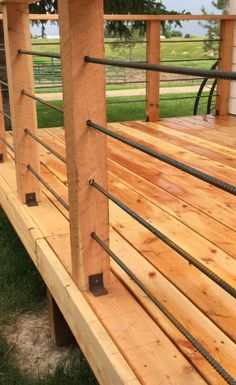 a close up of a wooden deck with ropes on the railings and grass in the background