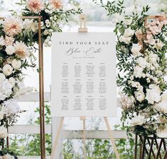 a seating sign with flowers and greenery on it for an outdoor wedding ceremony at the lake house