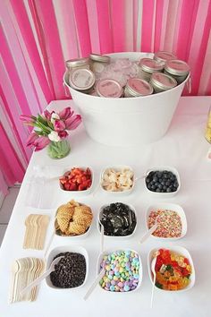 there are many different desserts in bowls on the table with pink stripes behind them