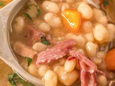 a white bowl filled with beans and ham