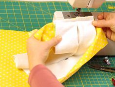 a person is sewing on a yellow and white cloth