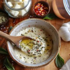 a wooden spoon in a white bowl filled with cream and herbs next to other ingredients