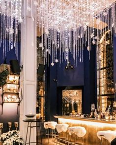 a bar with chandeliers hanging from it's ceiling and chairs around the bar