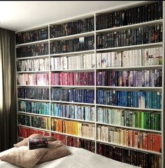 a bed sitting in front of a book shelf filled with books on top of it