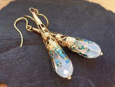 Elegant dangle earrings in gold with an opal (synth) that show beautiful sparks in the sun in light sky blue and sunny gold. The tear drop opals are facetted and remind also of moonstones and of oriental jewelry, of Art Deco, Art Nouveau and of paintings, where mysterious sorceresses prepare magic potions, illuminated by the fire. So this is a perfect gift for a fairy elf white-witchy woman who will certainly see this jewelry looks like a magic wand... I added verdigris patina to the tips and ma Elf Jewelry, Jewelry Magic, Aqua Earrings, Art Nouveau Earring, Terrarium Jewelry, Asian Jewelry, Teal Flowers, Fairy Jewelry, Prom Earrings