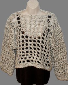 a white crocheted sweater with black buttons on the front and back, sitting on a mannequin's head