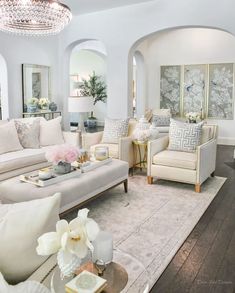 a living room filled with white furniture and lots of pillows on top of a rug